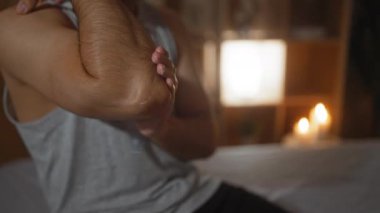 SPA 'da İspanyol bir adam, sakin bir güzellik odasında dirseğine losyon sürüyor. Hafif ışıklandırma ve sağIık için mumlar..