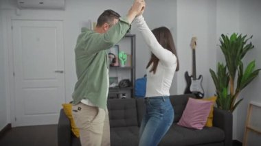 Mutlu bir çift modern dairelerinin oturma odasında dans eder, sevgi ve aile saadetiyle..
