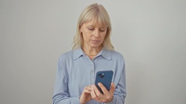 Neşeli sarışın kadın, neşeli bir şekilde gülümsüyor, pozitif jest yapıyor. Gözünün etrafına ok işareti koyuyor, izole edilmiş beyaz arka planda akıllı telefon kullanıyor.