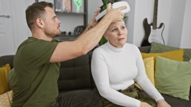 Bir kadın, modern bir oturma odasında bir erkeğin yardımıyla sanal gerçekliği tecrübe eder..