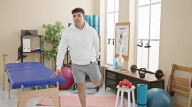 Modern bir fizyoterapi kliniğinde spor aletleri ve anatomik iskelet modeli olan genç bir adam..
