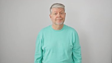 Gri saçlı, sıradan giyinmiş neşeli orta yaşlı bir adam, kameraya göz kırpıyor, kendine güvenen bir yüzle gülümsüyor. Barış işareti, zaferin sembolü. Hepsi izole edilmiş beyaz arkaplan.