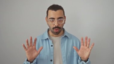 Kot gömlek giyen genç İspanyol adam şaşırmış bir halde, ağzı açık, korkmuş ve güvensiz bir şekilde izole edilmiş beyaz arka planda duruyor.