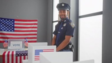 Gülümseyen bir erkek polis memuru Amerikan bayraklarıyla ABD seçim merkezinde onay veriyor.