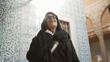 İstanbul 'un tarihi mekanında gözlüklü, gülümseyen bir kadın karmaşık döşemeleri hayranlıkla seyrediyor.