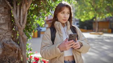 Genç bir kadın canlı bir şehir parkında selfie çekerken doğayla iç içe olur..