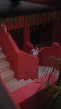 Günlük kıyafetli genç bir İspanyol kadın bali otelindeki egzotik bir merdivende sakin bir tropikal ortam sergiliyor..