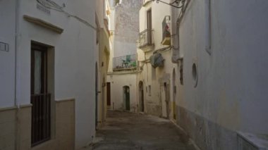 Gelibolu, Puglia, İtalya 'da dar, kaldırım taşı caddesi. Güneşli bir günde balkonları ve çamaşırları olan gösterişli, büyüleyici eski binalar..