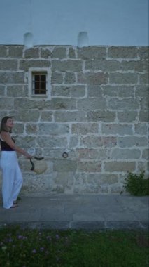 Genç bir İspanyol kadın Puglia, İtalya 'da kırsal bir villanın dışında geziniyor. Resimli taş mimarisini ve açık hava ortamındaki bereketli çevreyi gözler önüne seriyor..
