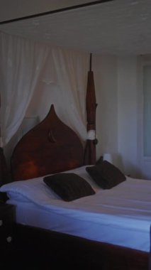 Zarif yatak odası, dört posterli yatak odası, beyaz çarşaflar, katıksız perdeler, ve bitişik bir banyo..