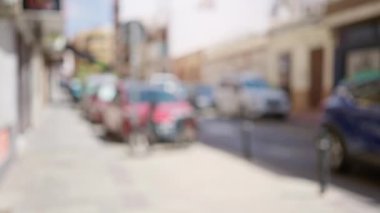 Bulanık bir arka plan şehir caddesini gösteriyor. Arabaları ve binaları olan şehir yaşamını ve açık hava ortamını gün ışığında gösteriyor.
