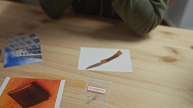 Ofiste elleri kelepçeli bir adam var. Arka planda delil fotoğrafları ve dosyalar var.