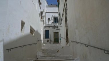 Ottuni, Puglia 'da dar, beyazlatılmış bir sokak. Açık mavi gökyüzünün altındaki büyüleyici Akdeniz binalarına uzanan merdivenleri ve korkulukları var..