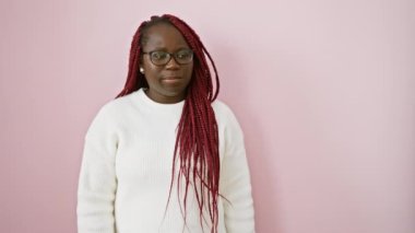 Örgü ören Afro-Amerikalı kadın izole pembe arka planı işaret ediyor.