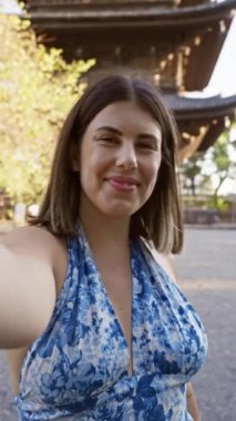 Kendine güvenen Latin güzeli, Kyoto 'nun to-ji tapınağında gündelik, eğlenceli bir özçekim anı yaşıyor. Barış işareti yüksekte, ışıl ışıl gülüşünü ve pozitifliğini yakalıyor..