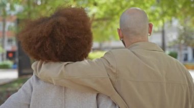 Şehir parkında kucaklaşan ırklar arası bir çift, şehir ortamında sevgi ve beraberlik gösteriyorlar..