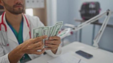 Beyaz önlüklü genç bir İspanyol adam masasında tıbbi malzemeler olan modern bir klinikte bize dolar sayıyor..