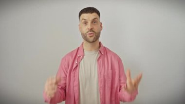 Şaşırmış genç İspanyol bir adam, ağzı tamamen açık, izole edilmiş beyaz arka plandan korkuyor, gömlek giyiyor ve şok olmuş bir ifade takınıyor..