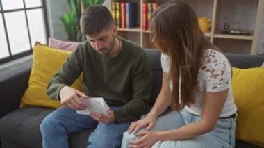 Bir erkek ve bir kadın, ortak ve ev hayatını resmeden rahat bir oturma odasında belgeleri gözden geçiriyorlar..