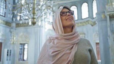 Başörtüsü içinde gülümseyen bir kadın İstanbul Camii 'nin iç kısımlarına hayran kalır.