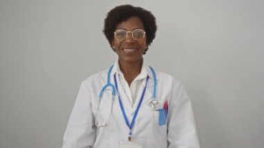 Kıvırcık saçlı, gözlüklü, gülümseyen ve izole edilmiş beyaz arka planı onaylayan Afrikalı Amerikalı kadın doktor..