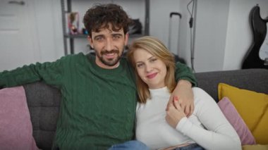 Mutlu çift, modern bir oturma odasında rahat bir kanepede sarılıyor, birlikte neşeli bir anı paylaşıyorlar..