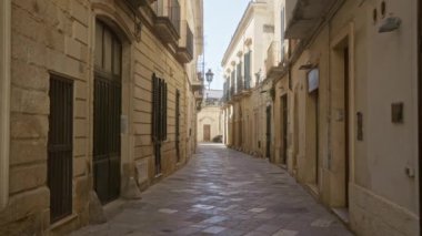 Lecce, İtalya 'nın tarihi şehrinde sessiz, dar bir kaldırım taşı caddesi. Kapalı pencereli geleneksel taş binalar sergileniyor..