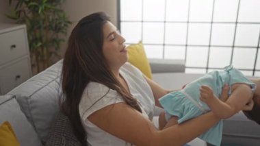 Sıcak bir oturma odasında küçük kızla oynayan bir kadın ev ortamında sevgi, neşe ve aile bağlarını yakalıyor..