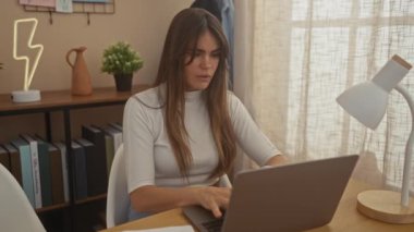 Ev ofis ortamındaki çekici genç bir kadın dizüstü bilgisayarla çalışırken stresli görünüyor..
