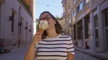 Güneşli bir günde dondurma külahının keyfini çıkaran güzel genç bir kadın Lecce, Puglia, İtalya 'nın büyüleyici sokaklarında yürürken.