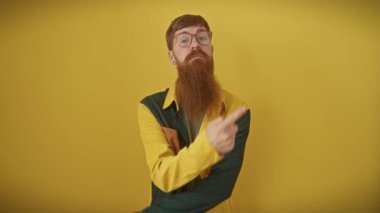 Ciddi yüzlü genç kızıl saçlı bir adam, kendine güvenerek, canlı sarı üzerinde reklam alanı gösteriyor. Gözlük takıyor, gömlek giyiyor ve güven gösteriyor..