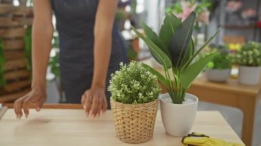 Gülümseyen kadın canlı bitkilerin arasında duruyor. Parlak, rahat bir çiçekçide.