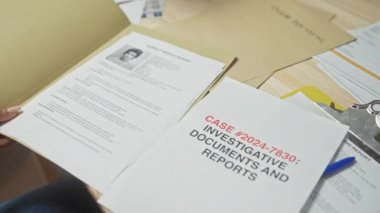 Soruşturma belgelerini ve polis merkezindeki bir olayla ilgili raporları inceleyen bir kadının ellerinin kapatılması.