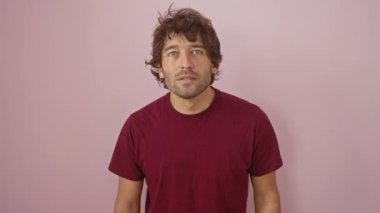 Bu tişörtü giyen İspanyol genç adam gururla bağırıyor, zaferi kutluyor ve kollarını kaldırmış pembe arka planda heyecanlanıyor.