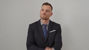 Takım elbiseli genç İspanyol bir adam, çenesinde parmak izi, düşünce, şüphe ve merak içinde, beyaz arka planda izole edilmiş, konsantre bir ifade sergiliyor.