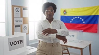 Oy verme kabinleri ve arka planında Venezuela bayrağı olan bir seçmen koleji odasında kendine güvenen bir kadın.