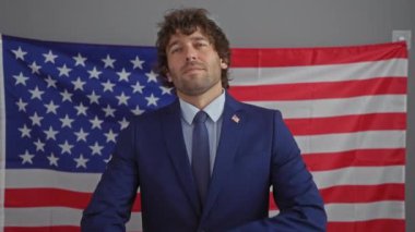 Amerikan bayrağına karşı takım elbiseli, sakallı, kendinden emin genç bir adam.