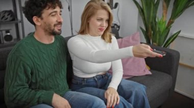 Keyifli bir çift, rahat bir oturma odasında televizyon kumandası için şakalaşıyor, boş zamanlarını sergiliyor..