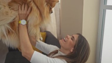 Hoş bir oturma odasında pomeranian 'ıyla bağ kuran mutlu bir kadın.