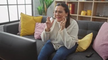 İspanyol kadın televizyon izlerken heyecanla kanepede parmaklarını çapraz yapıyor..