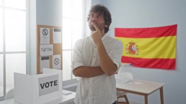 Düşünceli bir duruşu olan genç İspanyol bir adam, gömlek giyiyor ve eli çenesinde, İspanyol bir seçmen okulunda kafa karıştırıcı bir fikir üzerinde kafa yoruyor.