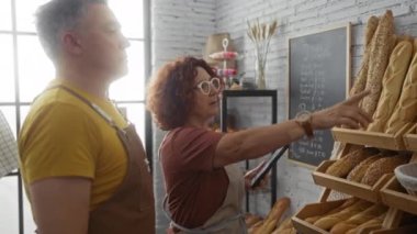 Fırıncılar ekmek sergisiyle birlikte çalışıyorlar, ekmek rafları ve hamur işleriyle tartışıyorlar ve işaret ediyorlar..