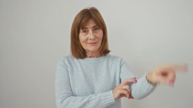 Süveter giyen neşeli orta yaşlı kadın, kendine güvenen bir zafer işareti gösteriyor, kameraya gülümseyen yüzüyle mutlu bir şekilde göz kırpıyor, izole edilmiş beyaz bir arkaplanda duruyor..