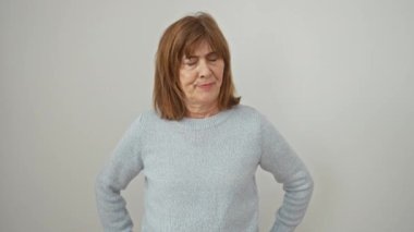Negatif duygular, gergin, şüpheci orta yaşlı kadın yalnız başına ayakta duruyor, üzgün beyaz arka planda rahatsız edici bir ifadeyle kaşlarını çatıyor..