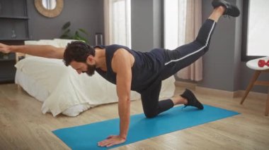 Formda bir adam, modern bir yatak odasında yoga minderi üzerinde dengeleyici bir egzersiz yapıyor ve sağlıklı bir yaşam tarzı sergiliyor..