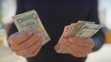 Orta yaşlı bir adam gündüz vakti dışarıda Birleşik Arap Emirlikleri 'ni sayıyor.