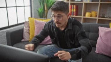 Gözlüklü heyecanlı genç İspanyol adam, kazanan koltukta, zaferi sevinçli çığlıklarla, kol hareketi başarısıyla yayıyor. İçeride mutlu kutlamalar..