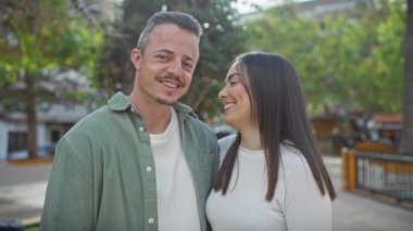 Gündelik giysiler içinde gülümseyen bir çift şehir parkında birlikte vakit geçiriyorlar, aşkı ve mutluluğu resmediyorlar..