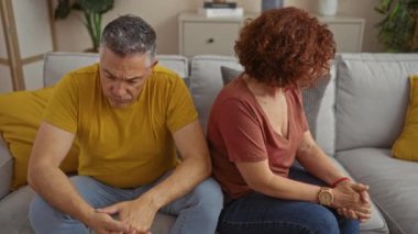 Oturma odasında üzgün üzgün oturan çift anlaşmazlık ya da anlaşmazlık öneriyor.