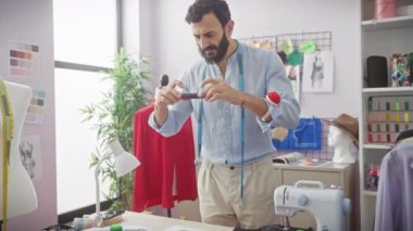 Moda tasarımları, dikiş makinesi ve mankenle renkli bir terzi dükkanında kumaşı inceleyen sakallı adam..